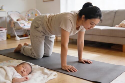 Jeune maman pratiquant la posture chat-vache du yoga post-partum sur un tapis dans son salon lumineux, avec son bébé dormant paisiblement à côté sur une couverture douce